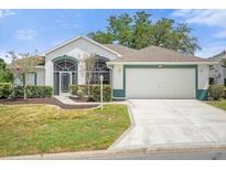 Single-story home with a two-car garage and well-manicured lawn at 21242 Braveheart Dr, Leesburg, FL 34748