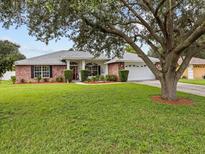 Brick house with a large tree and landscaped yard at 7438 Floral W Cir, Lakeland, FL 33810