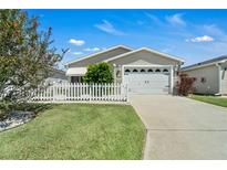 Tan one-story home with white picket fence at 1285 Chesnee Pl, The Villages, FL 32162