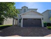 Two-story house with brown garage door and brick paver driveway at 7432 Marker Ave, Kissimmee, FL 34747