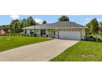 Single-story home with a two-car garage and a well-maintained lawn at 10604 Se 146Th Ln, Summerfield, FL 34491