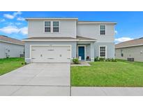 Two-story house with light gray siding, a two-car garage, and a well-maintained lawn at 1506 Finnigan Cir, Haines City, FL 33844