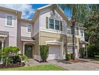 Two-story townhome with pink and beige exterior, green door, and attached garage at 570 Pinebranch Cir, Winter Springs, FL 32708