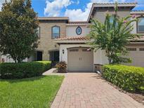 Exterior of townhome with a two-car garage, landscaping, and brick walkway at 13880 Arclid St, Orlando, FL 32832