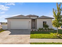 Modern one-story house with a two-car garage and landscaped lawn at 6262 Chorus Dr, Mascotte, FL 34753