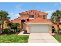 Two-story house with tile roof, two-car garage, and landscaped yard at 112 Paloma Dr, Davenport, FL 33837