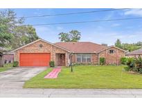 Brick ranch home with a large front yard and orange garage door at 897 Vicksburg St, Deltona, FL 32725