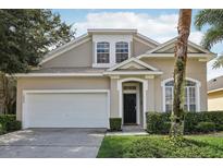 Two-story house with beige exterior, white garage door, and landscaping at 16838 Glenbrook Blvd, Clermont, FL 34714