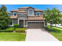 Two-story home with a modern facade, three-car garage and manicured lawn at 9101 El Caro Ln, Davenport, FL 33896