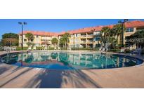 Community pool with surrounding lounge chairs at 6337 Parc Corniche Dr # 2104, Orlando, FL 32821