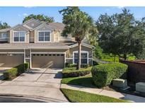 Tan two-story townhome with two-car garage, lush landscaping, and a palm tree at 400 Harbor Winds Ct, Winter Springs, FL 32708