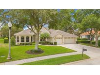 Single-Gathering home with three car garage, manicured lawn, and mature trees at 161 Hawkcrest Ct, Debary, FL 32713