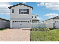 Two-story house with gray siding, a brick driveway, and landscaping at 519 Kennedy Dr, Lake Alfred, FL 33850