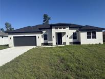 Modern single-story home with dark gray roof and garage at 2827 Sw 146Th Place Rd, Ocala, FL 34473