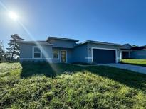 New single-story home with gray exterior, two-car garage, and grassy lawn at 13053 Sw 36Th Ct, Ocala, FL 34473