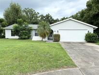 Single-story home with a white exterior, attached garage and neat lawn at 7817 Satsuma Ct, Orlando, FL 32835