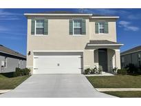 Two-story home with a double-car garage and neutral color palette at 2892 Waterlily Way, Poinciana, FL 34759