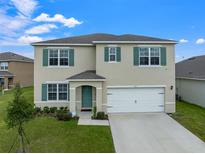 Two-story house with a two-car garage, landscaping, and a teal front door at 821 Sun Burst Rd, Winter Haven, FL 33880