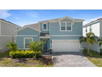 Two-story house with light blue exterior, two-car garage, and landscaping at 3625 Lily Ln, Davenport, FL 33897