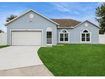 One-story house with light blue siding, white garage door, and green lawn at 815 Cardinal Way, Poinciana, FL 34759