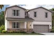 Two-story home with gray siding, stone accents, and a two-car garage at 3579 Dahlia Dr, Lake Hamilton, FL 33851