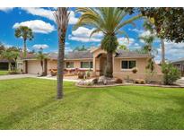 Single-story home with a well-manicured lawn, mature palm trees, and a two-car garage at 20820 Maxim Pkwy, Orlando, FL 32833