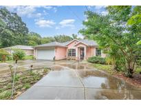 Pink house with a white garage door and a concrete driveway at 715 Unabelle Ave, Daytona Beach, FL 32117