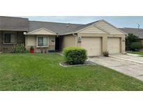 Tan brick exterior home with a two-car garage and well-manicured lawn at 5027 Se 109Th Pl, Belleview, FL 34420