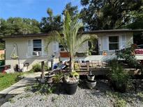 Tan house with a wooden deck, tropical plants, and gravel landscaping at 1117 E Hubbard Ave, Deland, FL 32724
