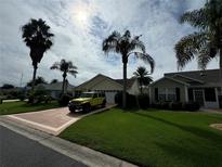 House exterior showcasing a well-maintained lawn, driveway, and palm trees at 1166 Johnston Path, The Villages, FL 32162