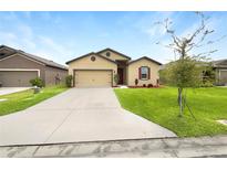 Tan one-story house with red door and attached garage at 6122 Dolostone Dr, Lakeland, FL 33811