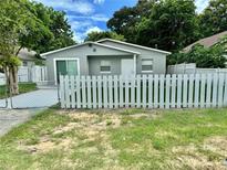 Updated bungalow with gray exterior, white picket fence, and a paved driveway at 117 N Observatory Dr, Orlando, FL 32835