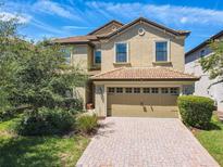 Two-story home with a tan facade and brick paver driveway at 1471 Rolling Fairway Dr, Davenport, FL 33896