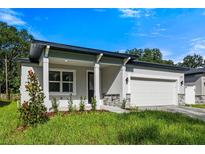 New construction home with gray exterior, white garage door, and landscaping at 2866 Lingo Ln, Orlando, FL 32822