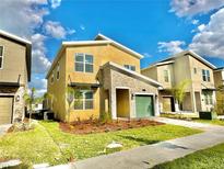 Two-story modern home with stone accents and a green garage door at 9095 Sommerset Hills Dr, Davenport, FL 33896
