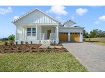 Charming farmhouse style home with a spacious covered porch and attached two-car garage at 487 Toscano St, Clermont, FL 34715