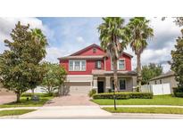 Two-story red house with a brick driveway, landscaping, and palm trees at 1934 Pantheon Dr, Winter Garden, FL 34787