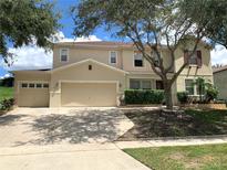 Two-story house with a beige exterior, two-car garage, and landscaping at 963 N Jacks Lake Rd, Clermont, FL 34711