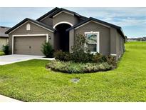 Gray house with a two-car garage and landscaped front yard at 1391 Swan Lake Cir, Dundee, FL 33838