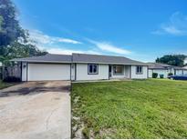 Newly renovated home features a white exterior, two-car garage, and well-maintained lawn at 1402 Valhalla St, Deltona, FL 32725