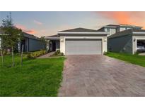 One-story house with gray garage door and landscaped lawn at 1833 Ross Hammock Ave, Groveland, FL 34736