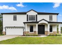 Two story home with white exterior, black accents, and stone at 18645 Seaview St, Orlando, FL 32833
