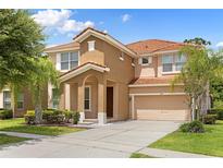 Two-story house with tan exterior, tile roof, and a two car garage at 290 Las Fuentes Dr, Kissimmee, FL 34746