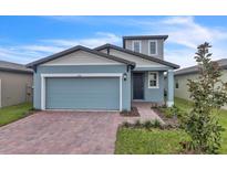 Two-story house with light blue garage door and brick driveway at 3793 Bluethread Way, Poinciana, FL 34759
