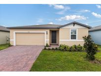 Tan house with dark brown door and brick driveway at 3170 Viceroy Ct, Poinciana, FL 34759