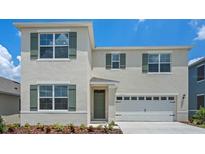 Two-story home with light beige siding, green shutters, and a two-car garage at 3540 Broadwing Blvd, Poinciana, FL 34759