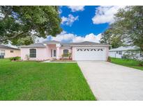 Pink house with a two-car garage and landscaping at 15639 Greater Groves Blvd, Clermont, FL 34714