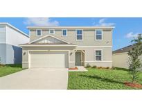 Two-story house with a beige exterior, two-car garage and landscaping at 1583 Aspen Ave, Davenport, FL 33837