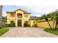 Two-story yellow house with a paved driveway and palm trees at 7315 Windham Harbour Ave, Orlando, FL 32829
