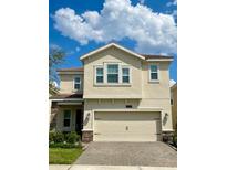 Two story home with light beige exterior, three car garage, and landscaping at 1075 Trappers Trail Loop, Davenport, FL 33896